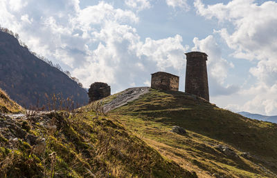 Scenic view of built structure on field against mountains and sky