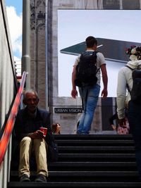 People on staircase in city against sky