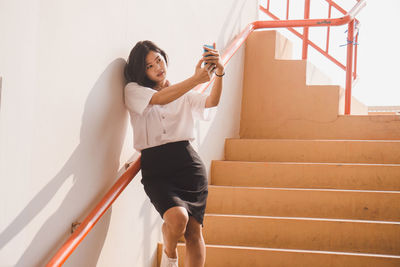 Young woman on staircase against wall