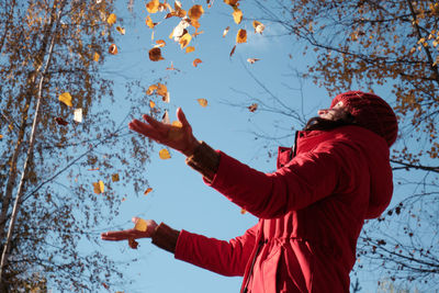 Low angle view of man with arms raised against sky