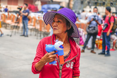 Woman looking away while standing on street in city