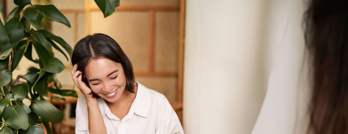 Portrait of young woman looking away while standing at home