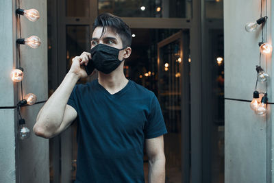 Close-up of young man wearing mask talking on mobile phone outdoors