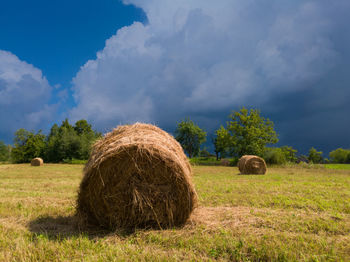 Hay bales on field against sky