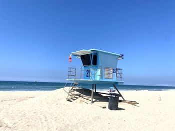 Lifeguard hut on beach against clear blue sky