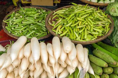 Fresh okra, chili peppers, radishes, and cucumbers on display at a market stall. hue, vietnam.
