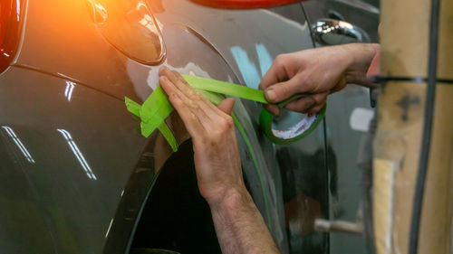 Cropped hands applying tape on car