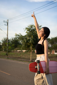 Side view of young woman standing against the sky