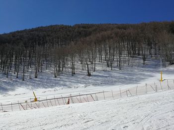 Scenic view of snowcapped field against clear sky during winter