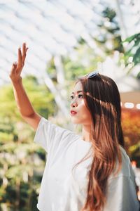 Young woman shielding eyes while standing by railing