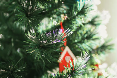 Decorated christmas tree branches with wooden red toy house