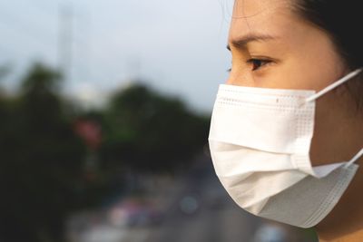 A woman wearing a surgical mask is standing on a flyover.