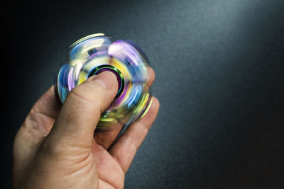 Close-up of hand spinning fidget spinner against wall