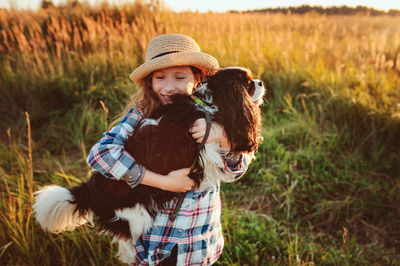 Girl holding dog on field