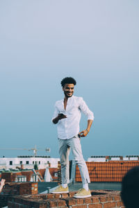 Full length of young man standing against clear sky