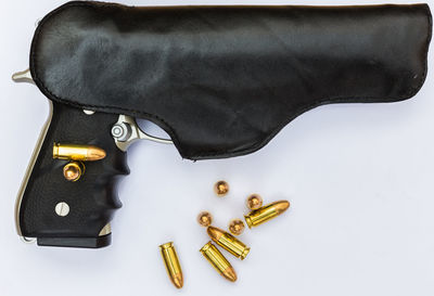 Close-up of gun and bullets over black background