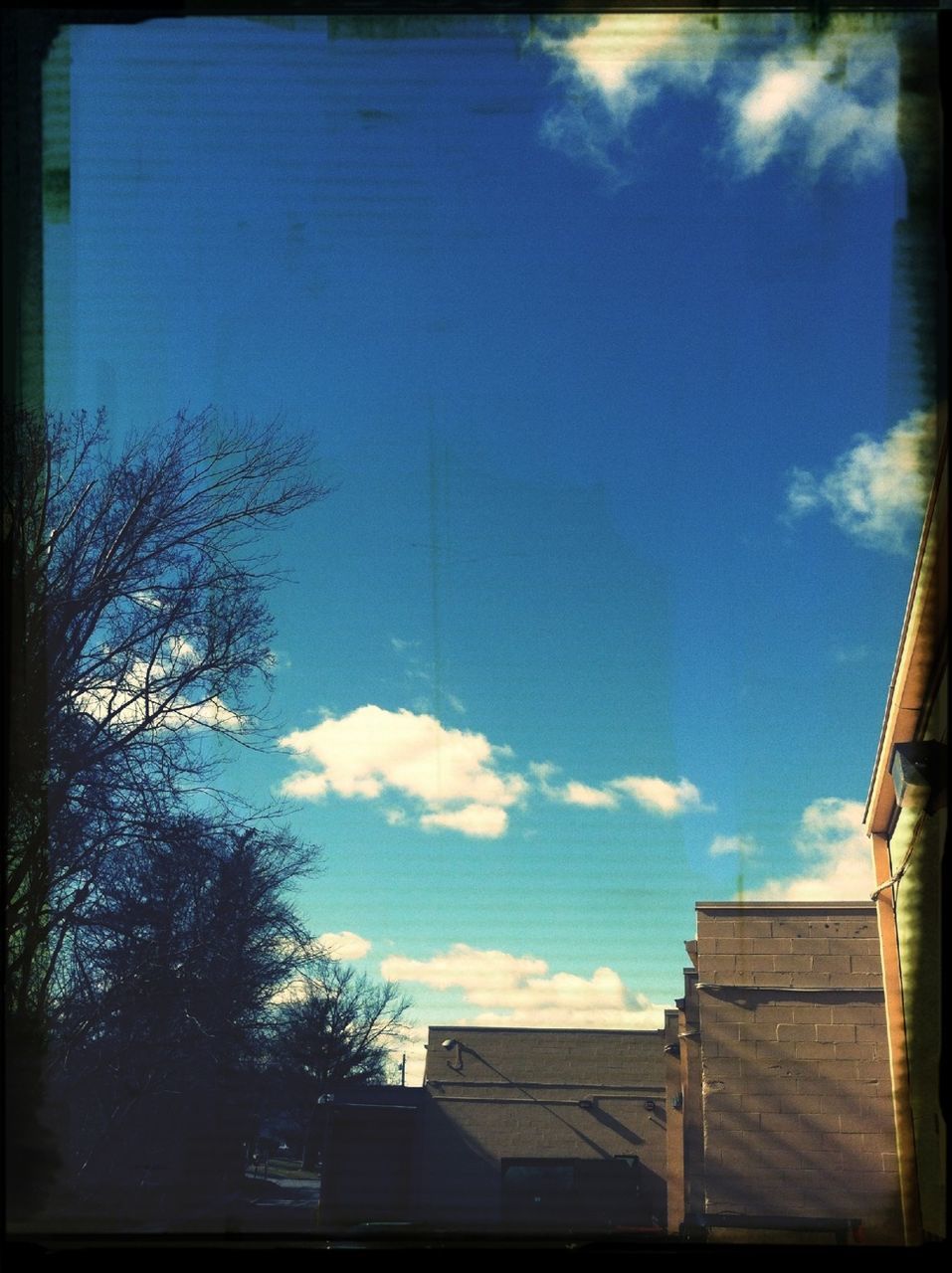 building exterior, architecture, built structure, transfer print, sky, blue, low angle view, auto post production filter, tree, bare tree, house, cloud - sky, cloud, residential structure, residential building, building, outdoors, day, no people, city