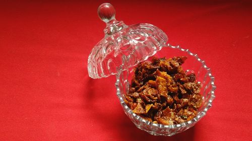 High angle view of pickle in bowl with lid over red background