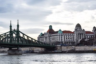 Bridge over river against cloudy sky