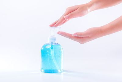 Close-up of hand holding bottle against white background