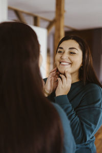 Woman looking in mirror and smiling at home