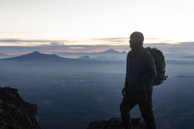 Man standing on mountain against sky during sunset