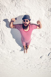 Full length of man screaming while lying on sand at beach