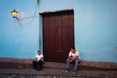 Full length of man sitting outside house