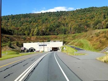 Road amidst trees and mountains against sky