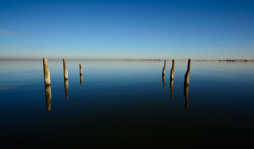 Wooden post in lake water against clear sky