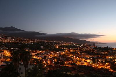 High angle view of illuminated buildings in city against clear sky