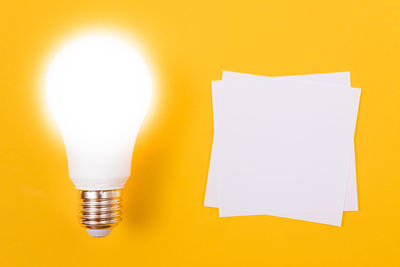 Close-up of illuminated light bulb against yellow wall