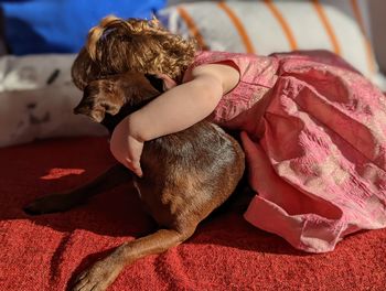 High angle view of girl lying on bed with dog