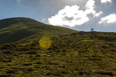 Low angle view of hikers standing on mountain against sky