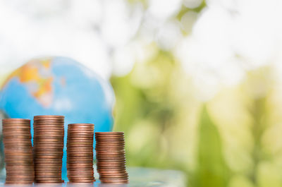 Stack of coins with globe on table