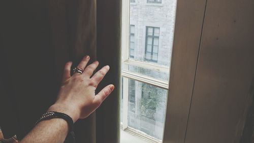 Cropped hand of woman touching curtain