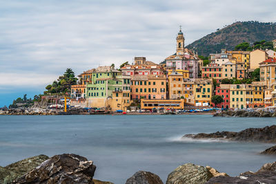 Buildings by sea against sky