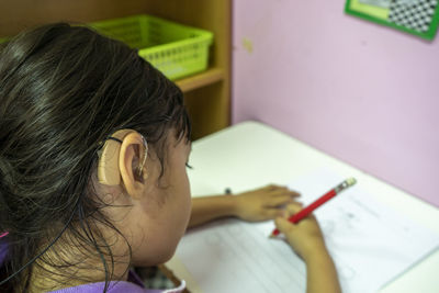 Close-up of woman writing on book at home