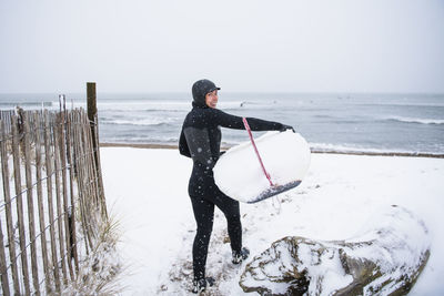 Man standing on beach against sky during winter