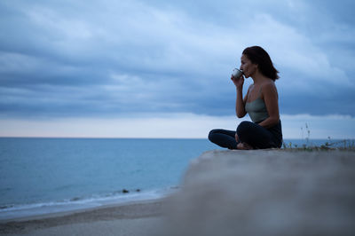 Woman having a cup of tea after a yoga session by the sea.