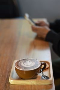 Close-up of hand holding coffee cup on table