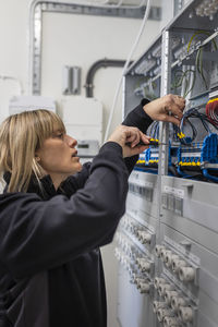 Female technician checking cables in control room at industry