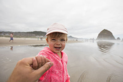 Portrait of young girl holding fathers hand at cannon beach.