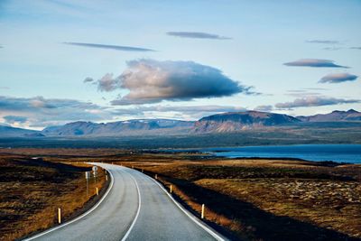 Road leading towards mountains against sky