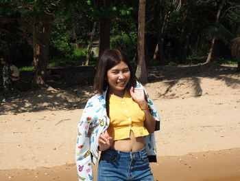 Portrait of smiling young woman standing on land