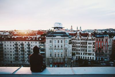 Man in city against sky during sunset