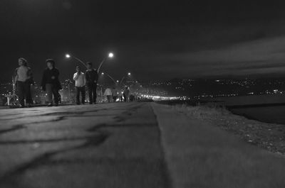 View of pathway along trees at night