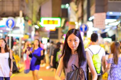Portrait of smiling man standing on illuminated street at night