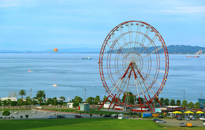 Ferris wheel by sea against sky