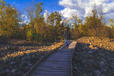 Rear view of person walking on railroad track
